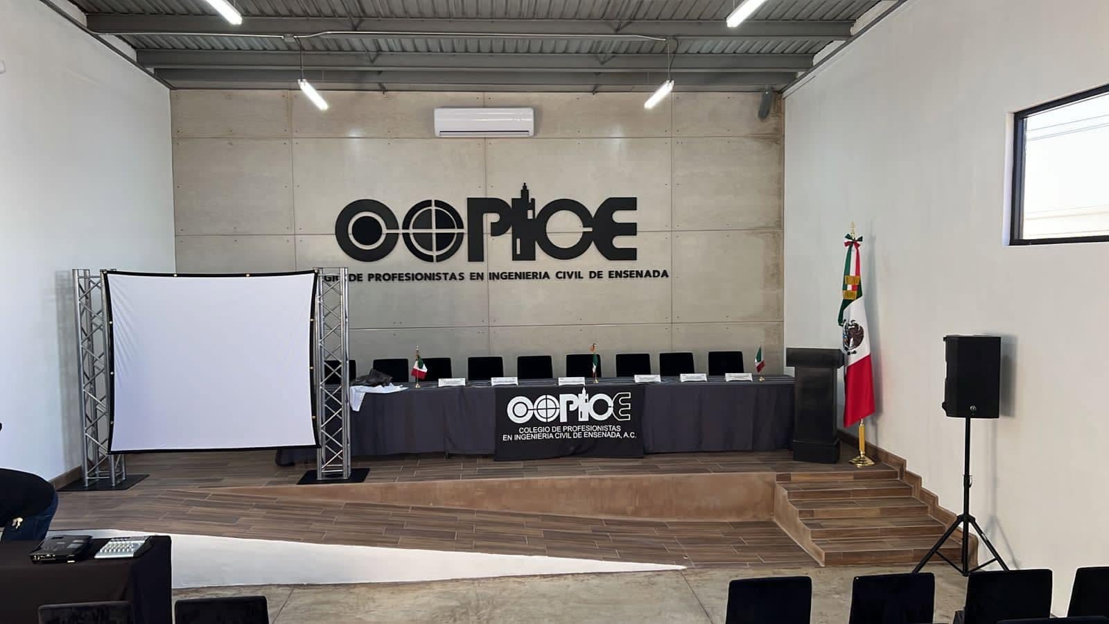 Salón de sesiones del Colegio con el logotipo de COPICE en la pared, presídium y pantalla de proyección